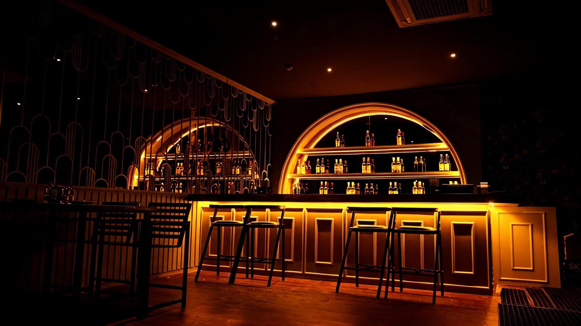 Bier Loft's arched backlit bar with high stools at night